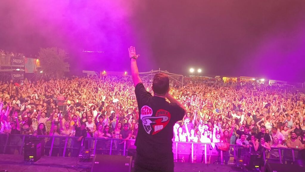 Javi Rodríguez animando desde el escenario a un público con las manos levantadas.